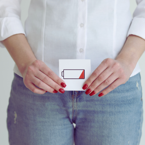 a woman holding a piece of paper with a battery on it indicating low libido